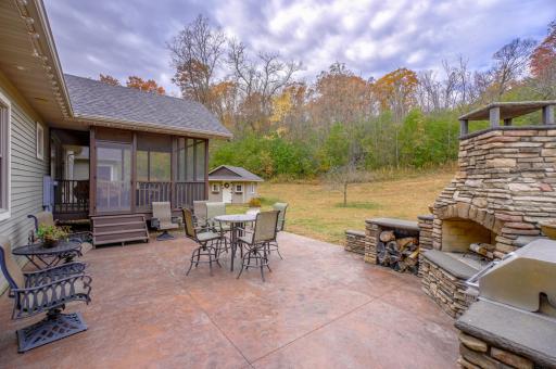 Spacious concrete patio featuring a built-in grill and wood fireplace.