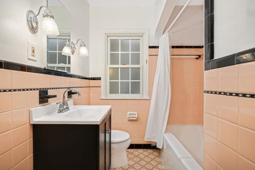 Charming mid-century vintage bathroom featuring classic peach and black ceramic tilework. This beautifully preserved space blends timeless retro character with updated functionality.