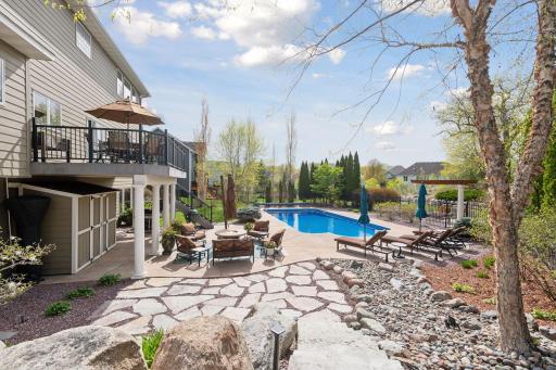 Experience resort style living in your own backyard! Stone steps lead from the side of the house down to the paver patio.