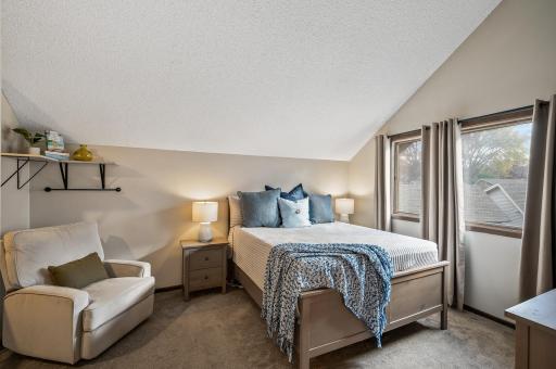 A cozy armchair sits in one corner, perfect for reading, while a stylish nightstand on either side of the bed holds modern lamps and personal touches.