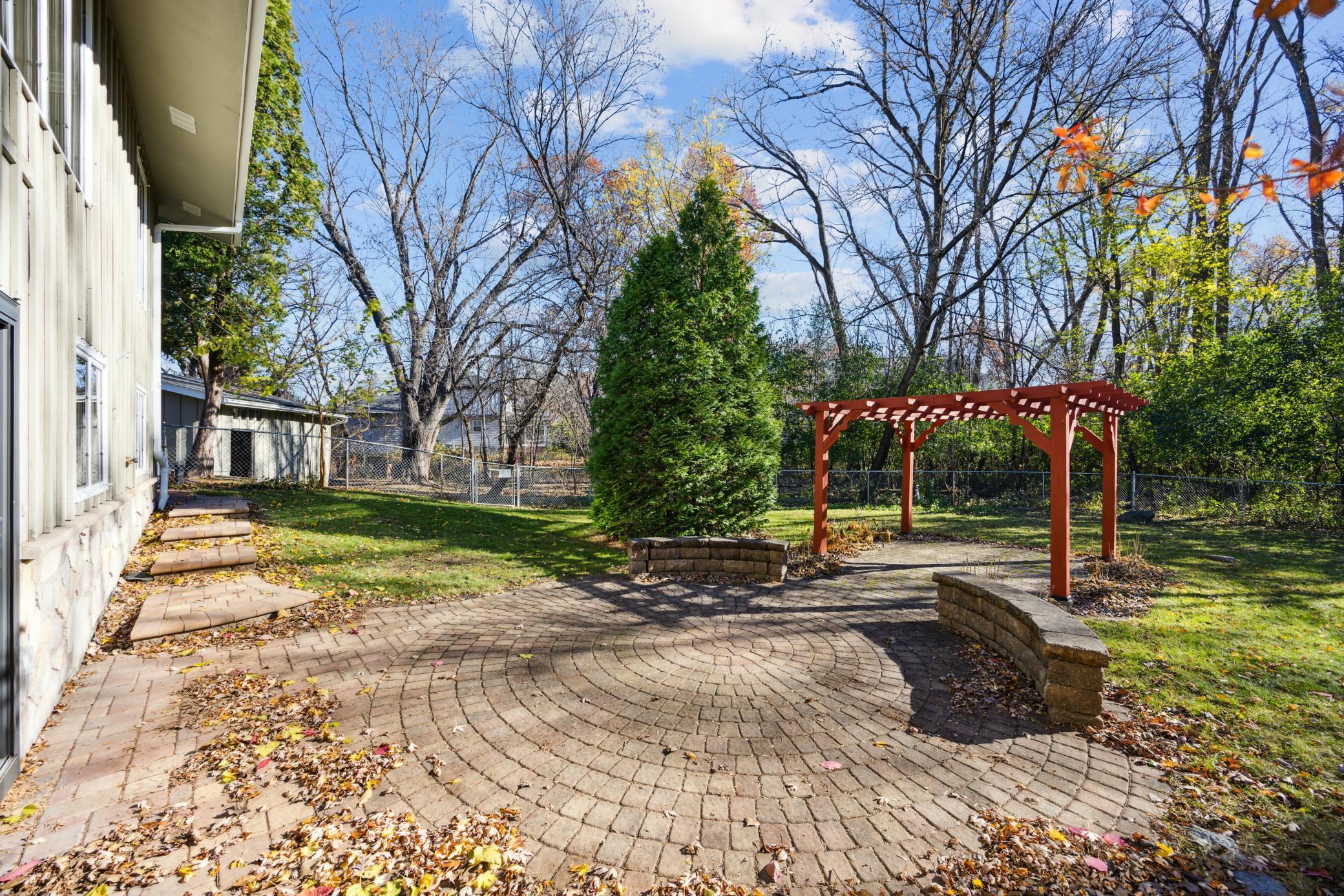 BeautifulPatio area with purgola and stone benches.