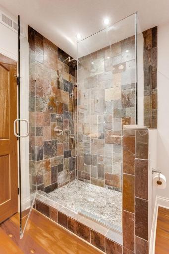 3/4 bath walk in shower with natural stone and a glass door.