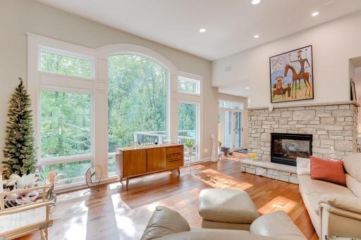 Soaring ceilings, wall of floor to ceiling windows and newly refinished open staircase to the lower level for an open airy space. Recessed lighting and a natural stone gas fireplace exude a cozy elegance.