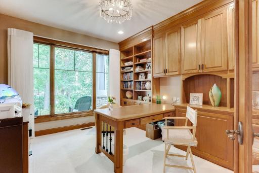 Executive Office with views to the front yard. New carpet installed in 2020, glass French doors and custom cherry cabinets and desk.