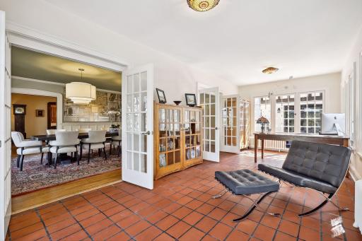 Main level sunroom with east, west, and southern exposure. French doors lead to the front patio. Original tile floors. A wonderful spot for an office, sitting room, or indoor garden. Views of Lake of the Isles.