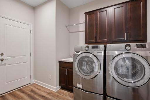 Main floor laundry and mudroom makes single-level living so easy. Notice the helpful utility sink and overhead cabinets.