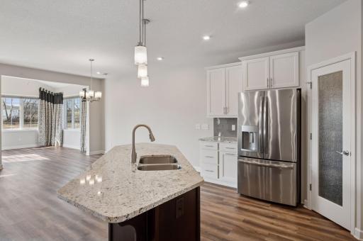 Large kitchen island with walk-in pantry and stainless steel appliances, great for cooking.