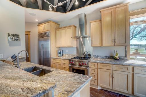 The gourmet kitchen is a dream, featuring birch cabinetry, high-end stainless steel appliances, including a Wolf range oven and Sub-Zero refrigerator, granite countertops, a breakfast bar, and access to the patio for grilling!