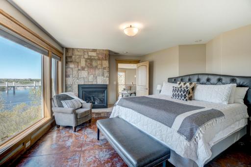 Primary bedroom with a cozy fireplace, windows showcasing the unmatched views, his-and-her bathrooms, one with a soaking tub and double vanities, and a massive walk-in closet.