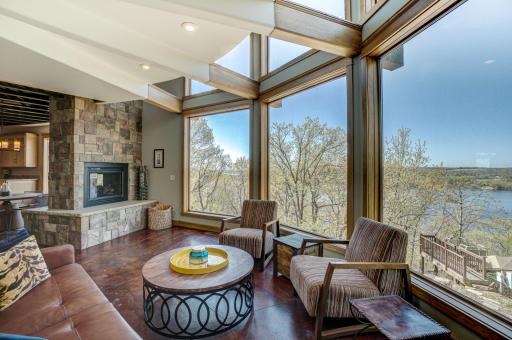 Inside, the light-filled open layout boasts floor-to-ceiling windows framing the river, and a double-sided gas fireplace that adds warmth and sophistication.