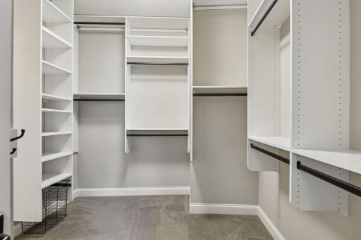 Built-in organizational components are found in the primary walk-in closet