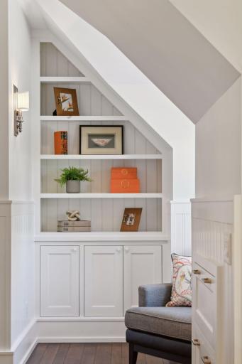 This sun-filled nook in the upper-level hallway invites you to curl up with a good book - or use as a perfect spot for a writing desk - the built-ins feature hanging file drawers.