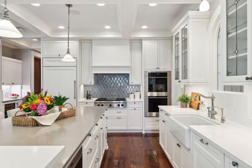 Well-equipped with professional appliances from Wolf, Sub-Zero, and Asko - the kitchen features a built-in microwave, double wall ovens with a warming drawer below, and a gas cooktop with infrared griddle.