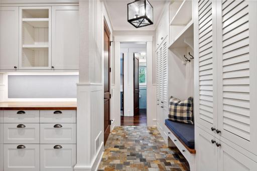 Stay effortlessly organized in this well-appointed Mudroom, featuring a convenient drop station, built-in bench, louvered-door lockers, and a spacious walk-in coat closet.