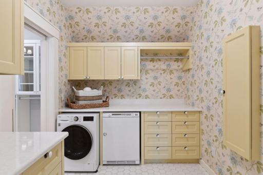The upper level Laundry Room is a charming space with custom cabinetry, a built-in ironing board and Cambria countertops.