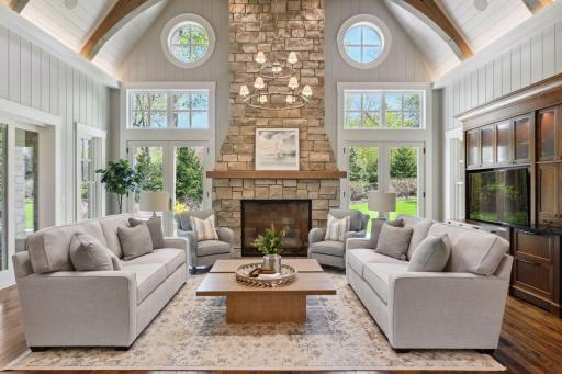 The home enjoys a true Great Room with large windows and a soaring vaulted ceiling accented with exposed timber trusses. Crafted from walnut, the custom built-in entertainment center features pull-out shelving and soft close cabinetry.