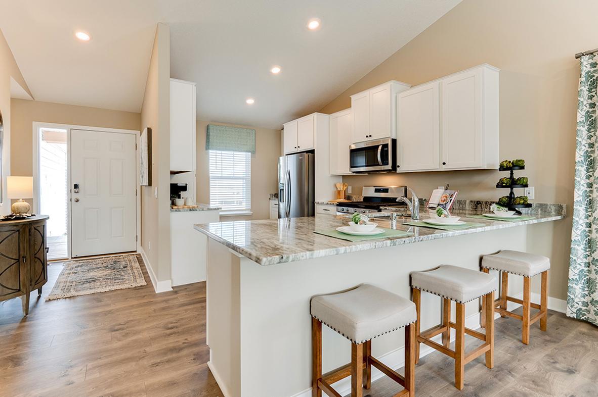 Open and spacious kitchen with stainless steel appliances, kitchen window, and quartz countertops. Model home photo, actual home will vary in finishes.