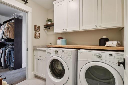 Upper level laundry room with a sink and plenty of cabinet storage