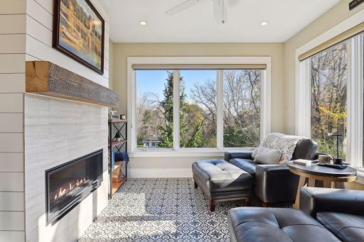 Cozy sun room with wooded views, electric heated floors, and gas burning fireplace.
