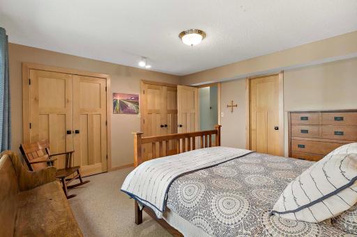 Main-level bedroom has multiple closets with maple wood doors. Door on right leads to main floor full bath.