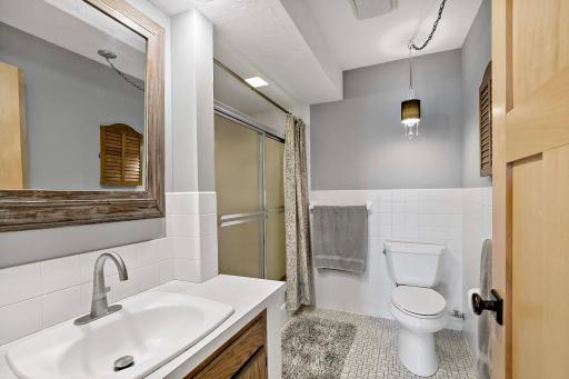 Main level full bath with tile floors and backsplash.