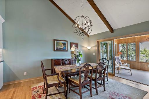 Dining area with cedar-beamed, vaulted ceiling, and glass sliding doors to access the four-season porch.