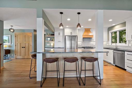The custom maple hardwood island is illuminated by pendant lighting and has a Brazilian quartzite countertop.