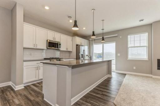 (Photo of an inventory home, actual homes finishes will vary) This spacious kitchen features a large center island, quartz countertops, LVP floors and more!