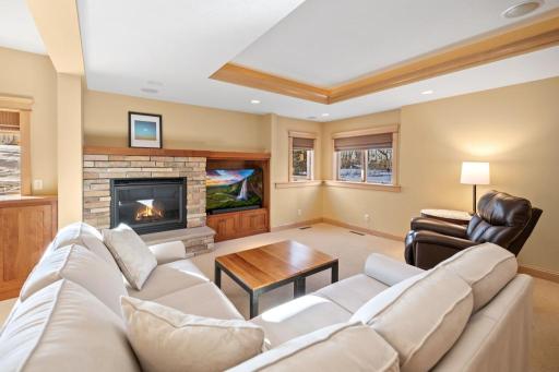A gas fireplace with a striking stone surround anchors the room, while recessed lighting creates a warm, inviting atmosphere perfect for relaxing or gathering with friends.