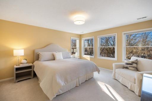The primary suite is a serene retreat, where light pours in through a wall of windows that frame stunning views of Lake Goetschel.