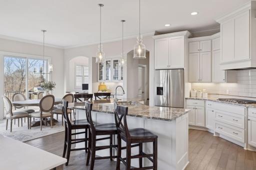 The stunning eat-in kitchen offers enameled cabinets, granite countertops, center island, beverage bar, and planning center.