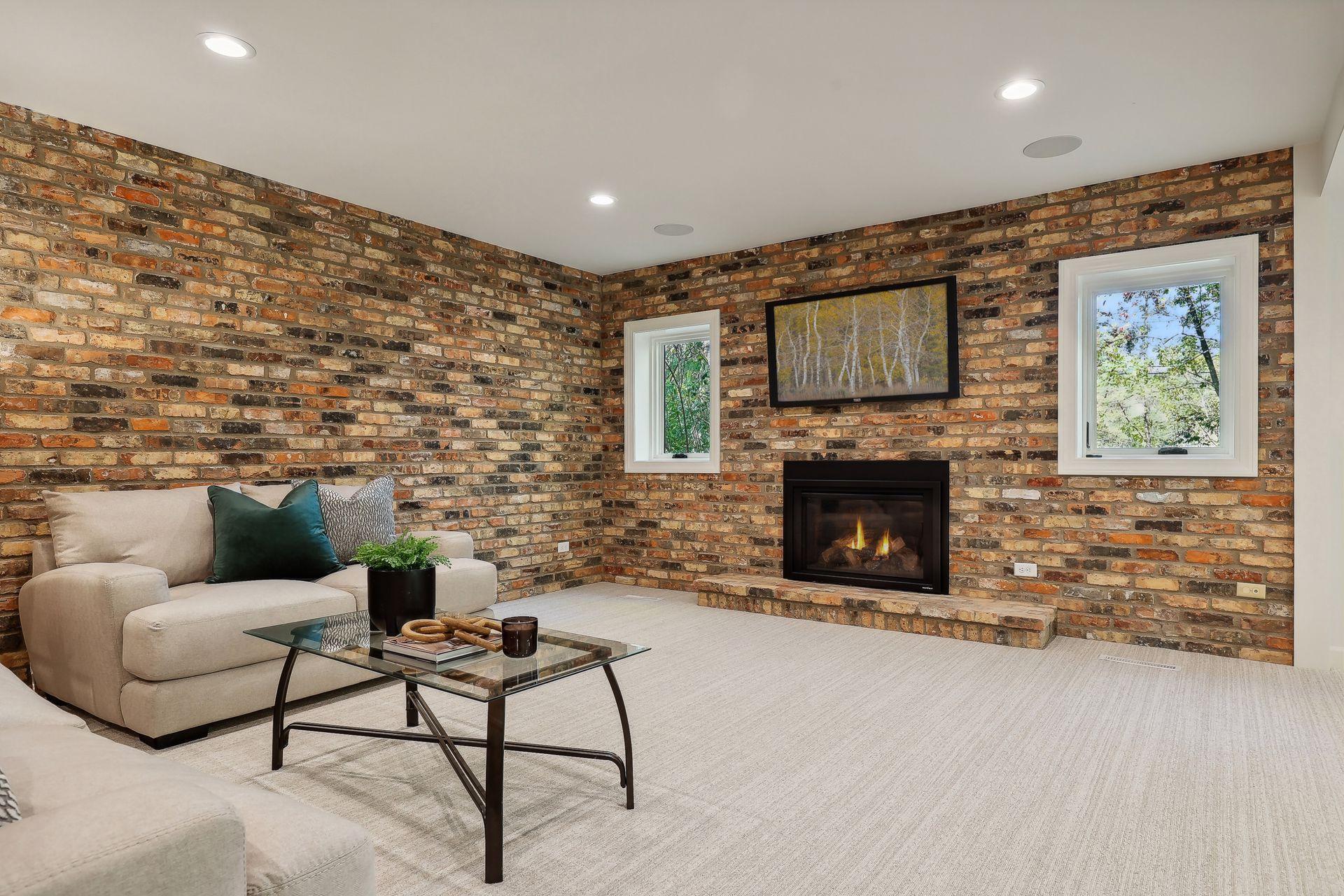 This inviting lower level family room features a bright and cozy atmosphere, highlighted by a charming fireplace.
