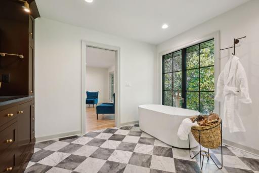 This beautiful primary bath features modern checkered tile floors complemented by warm wood cabinets, creating a chic and inviting atmosphere.