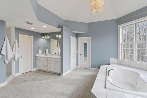 The Primary Bathroom is a private spa with a large jetted bathtub, comfort height vanity with two sinks and a beautiful designer light fixture.