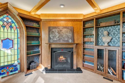 Corner wood burning fireplace with slate tile surround and antique mantel and exposed oak beams