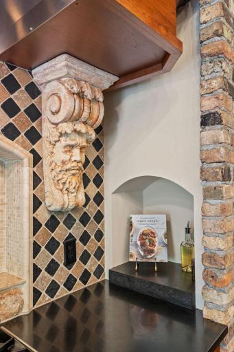Honed granite countertops with travertine tile backsplash offers decorative niches behind and next to the range