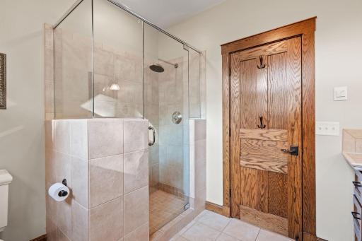 Shower features full tile surround and frameless glass enclosure. Ceramic tile flooring with radiant in-floor heat.