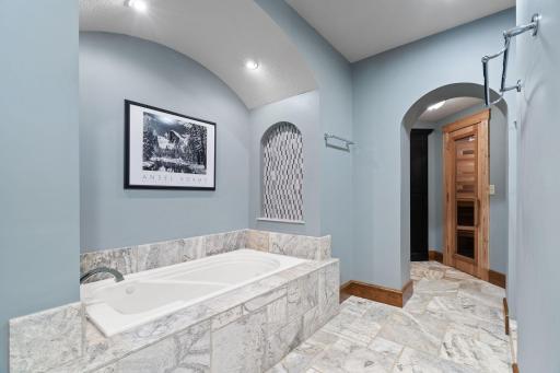 Jetted tub situated on a travertine tile deck and surround with decorative niches
