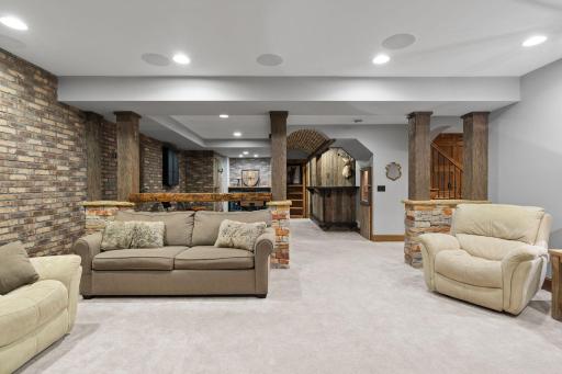 Rustic beam (can be removed) supported by stone wrapped pillars serves as a raised top for stools and defines the sapce
