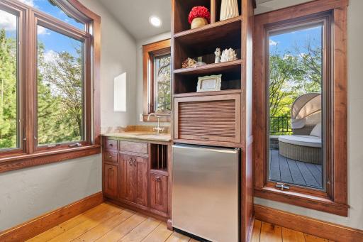 Hickory wet bar features inset doors, honed granite top with round sink, roll-out storage, appliance garage, open display shelving and a beverage refrigerator