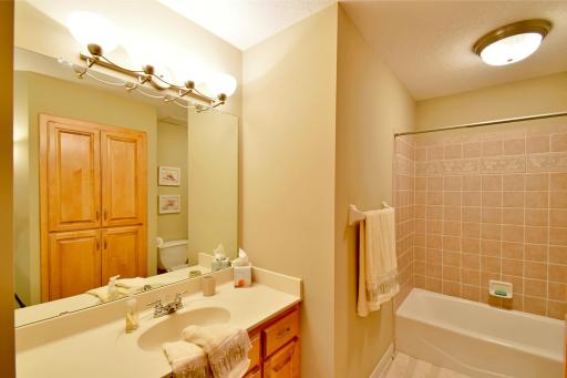 Upstairs full bath with large linen closet, custom tile & solid surface counter