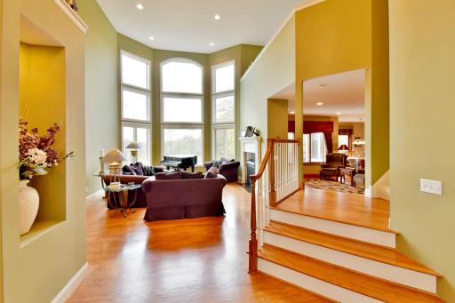 Vaulted entry leading to open living room space with floor to ceiling windows, double sided gas fireplace, recessed lighting, beautiful hardwood flooring throughout main level.