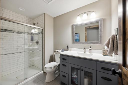 5th bathroom in lower level with tiled shower. Note the custom koehler drains in the showers throughout the home.