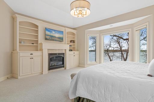 Custom built-ins and a gas fireplace add warmth and charm to the owner's suite, creating the perfect ambiance for cozy winter nights by the lake.