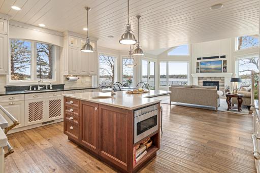 Incredible kitchen seamlessly flows into the cozy hearth room, featuring a floor-to-ceiling gas fireplace and walls of windows that offer serene lake views and direct access to the oversized deck.