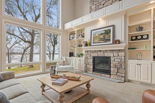 Elegant gas fireplace flanked by custom built-ins anchors the living room, while expansive windows frame spectacular views of Turtle Lake.
