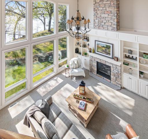Breathtaking view from the upper level overlooking the catwalk and soaring two-story living room—framed by walls of windows with panoramic views of Turtle Lake.