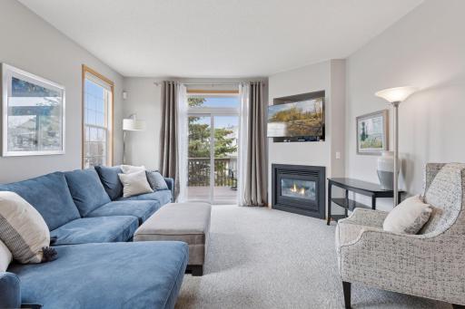 Spacious, sunny living room with gas fireplace and deck access