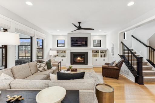 Enjoy natural light streaming through large windows with chic black frames, highlighting the spacious seating area complete with built-in bookcases and fireplace add to the ambience.