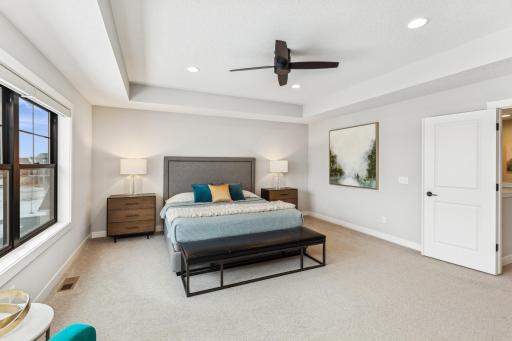 The primary suite is a luxurious retreat, featuring a stunning box vault ceiling that adds a sense of grandeur, complemented by a ceiling fan for enhanced comfort and style